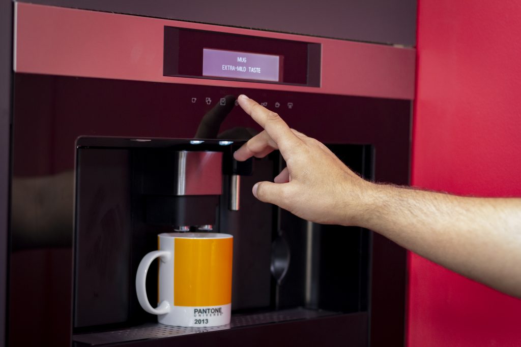 Hand operating coffee machine with yellow mug